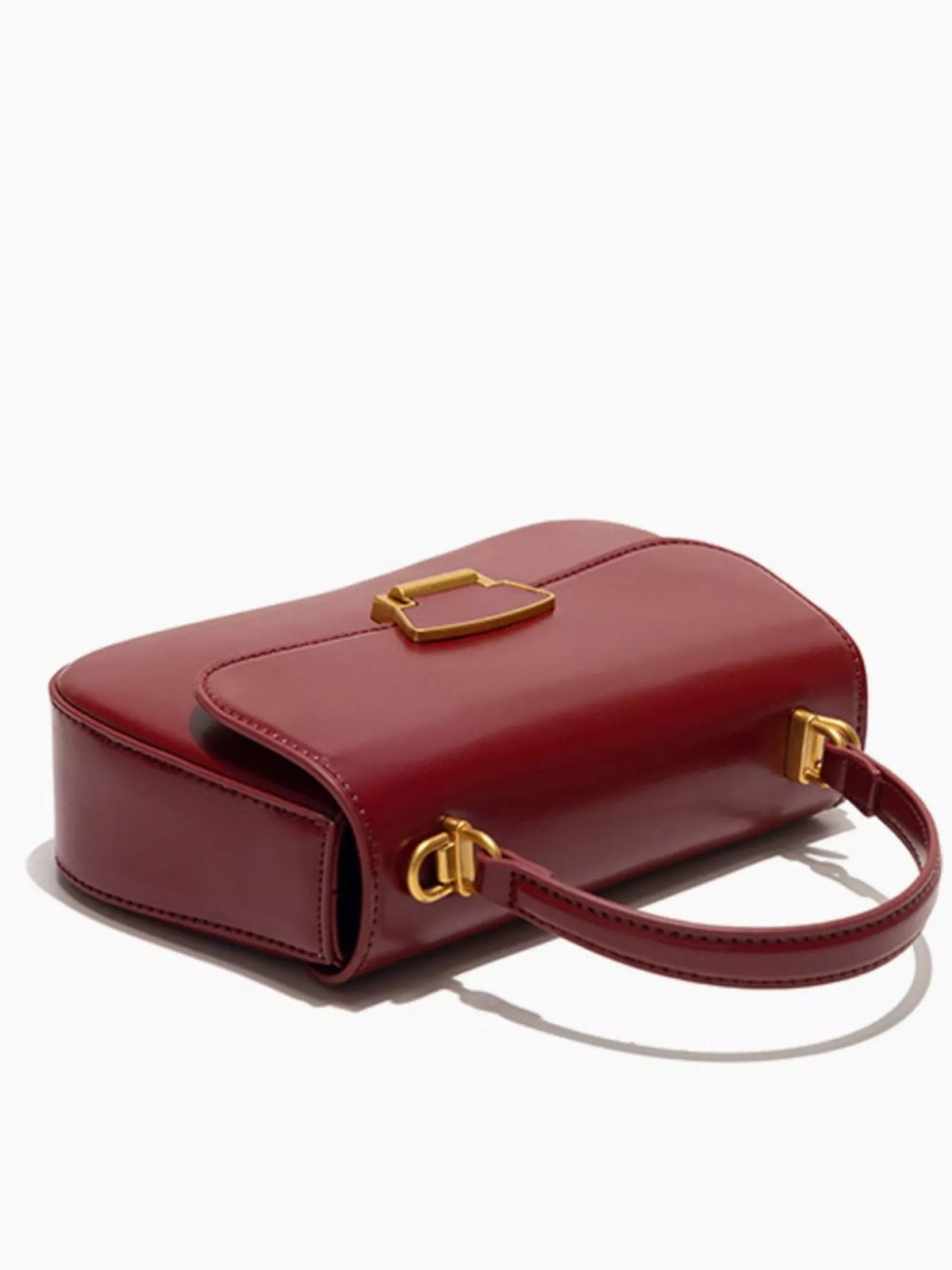 Small burgundy PU leather crossbody bag with a structured rectangular silhouette, stitched flap, gold-tone clasp, and long matching shoulder strap.
