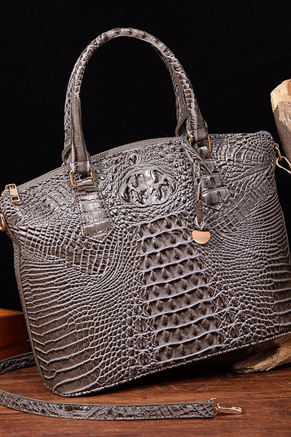Structured medium gray PU leather handbag with crocodile-inspired embossed texture, rounded top handles, zip closure, detachable shoulder strap, and hanging charm.