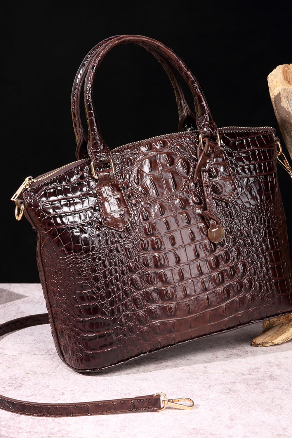 A medium dark brown PU leather handbag with a structured silhouette, crocodile-embossed texture, rounded top handles, zip-top closure, and detachable shoulder strap.