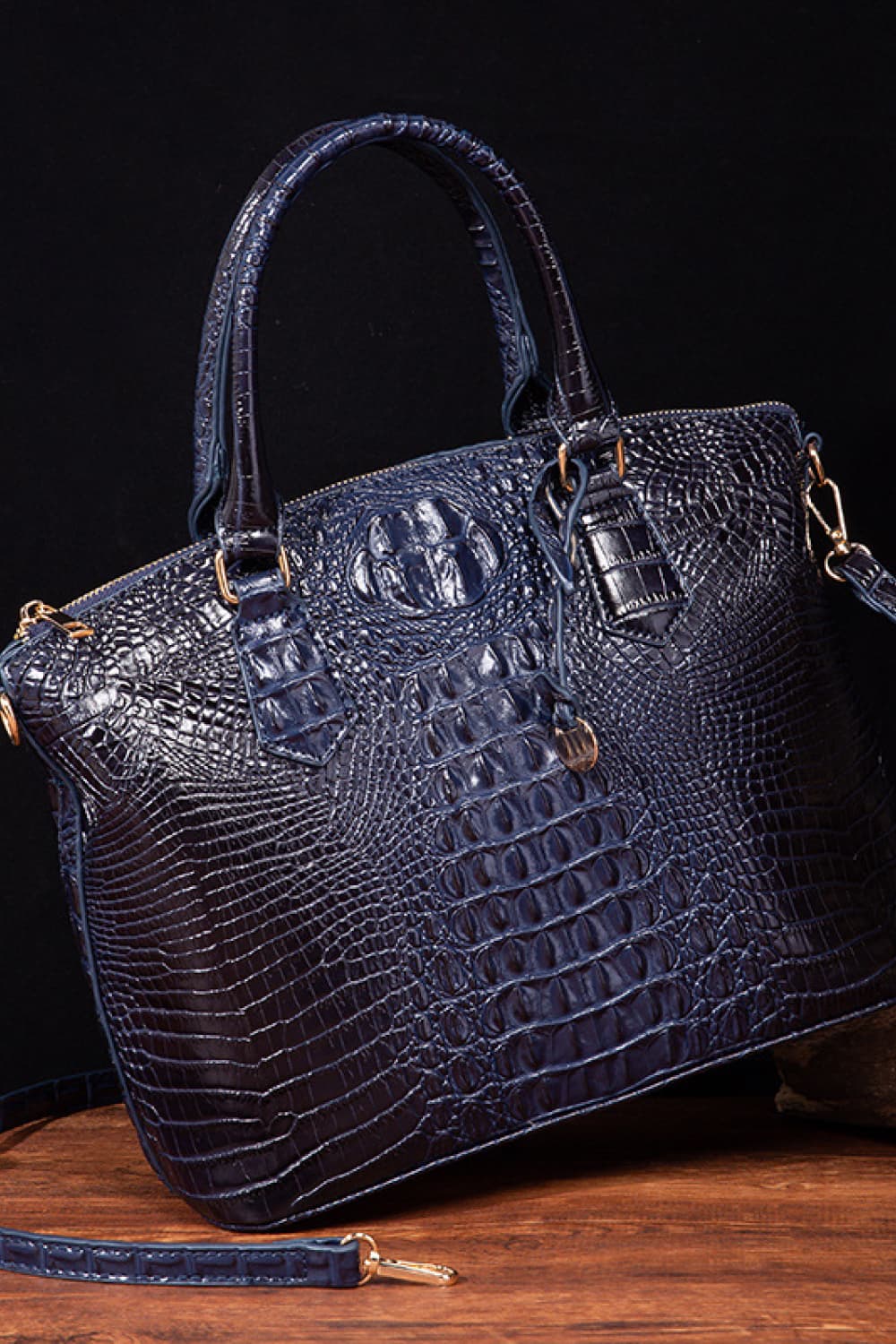 A medium navy PU leather handbag features a structured silhouette, crocodile-embossed texture, rounded top handles, zip-top closure, and an attached shoulder strap.