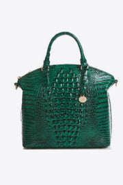 A medium green PU leather handbag features a structured tapered silhouette, crocodile-inspired embossed texture, rounded top handles, and a decorative hanging charm.