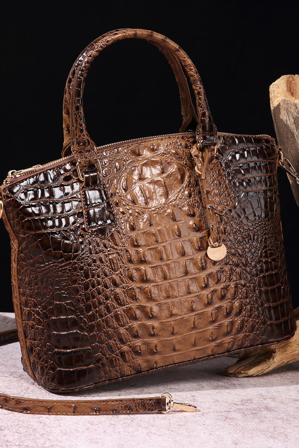Medium brown PU leather handbag with a structured tapered silhouette, rounded top handles, crocodile-inspired embossed texture, zipper closure, hanging charm, and removable shoulder strap.