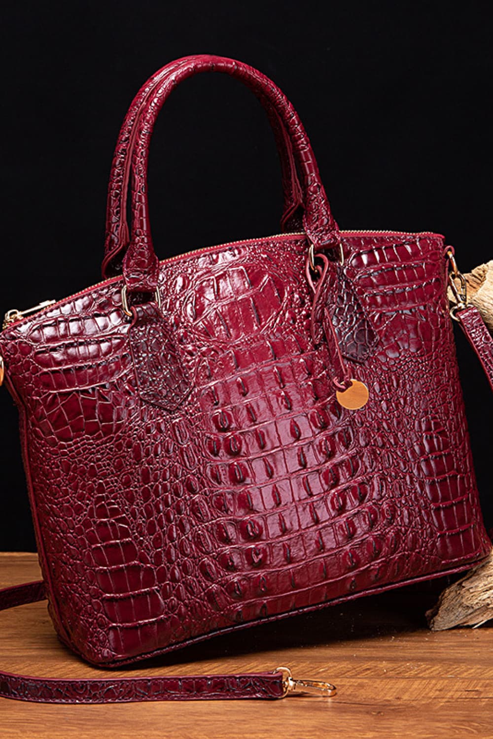 Burgundy medium PU leather handbag with a softly tapered structured silhouette, rounded top handles, crocodile-inspired embossed texture, removable strap, and hanging charm.