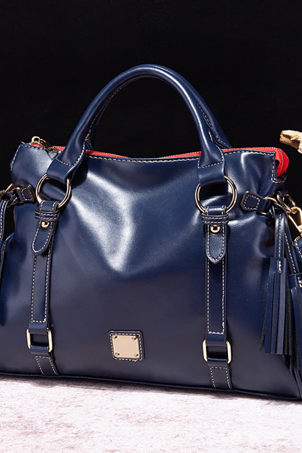 Large navy PU leather handbag with a softly structured silhouette, rounded top handles, gold-tone hardware, adjustable side straps, and tassel accents.