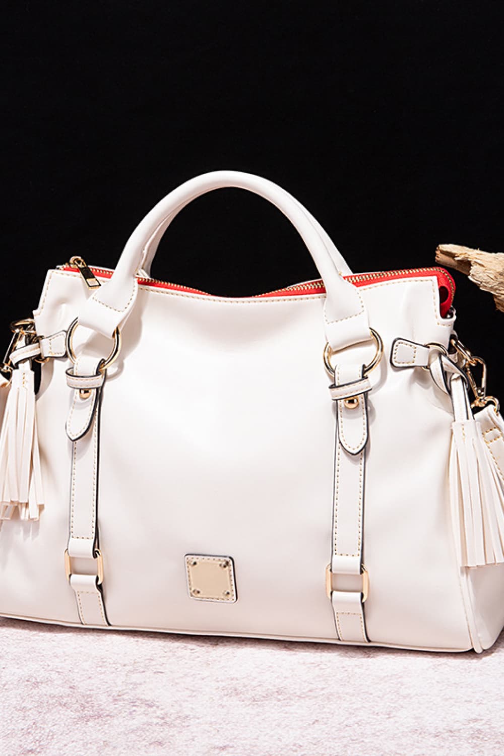 Large white PU leather handbag with rounded top handles, a zip closure, gold-tone hardware, adjustable strap details, and long tassel accents.