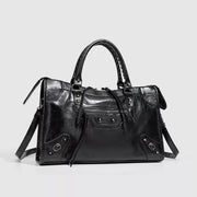 Black medium PU leather handbag with dual top handles, a structured silhouette, front zip pocket, decorative strap details, and a detachable shoulder strap.