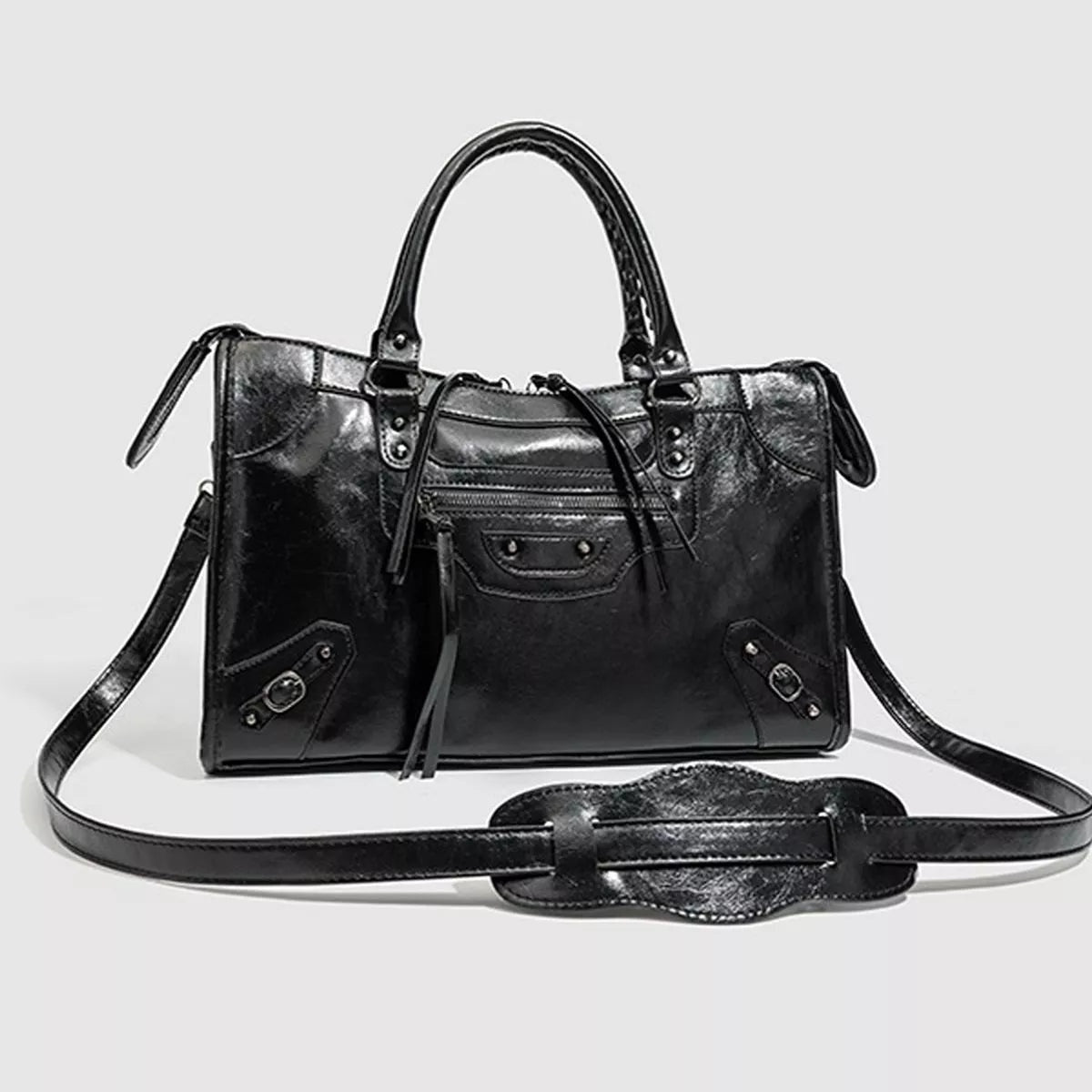 Black medium PU leather handbag with a structured silhouette, dual top handles, long shoulder strap, and multiple zippered and decorative front pockets.