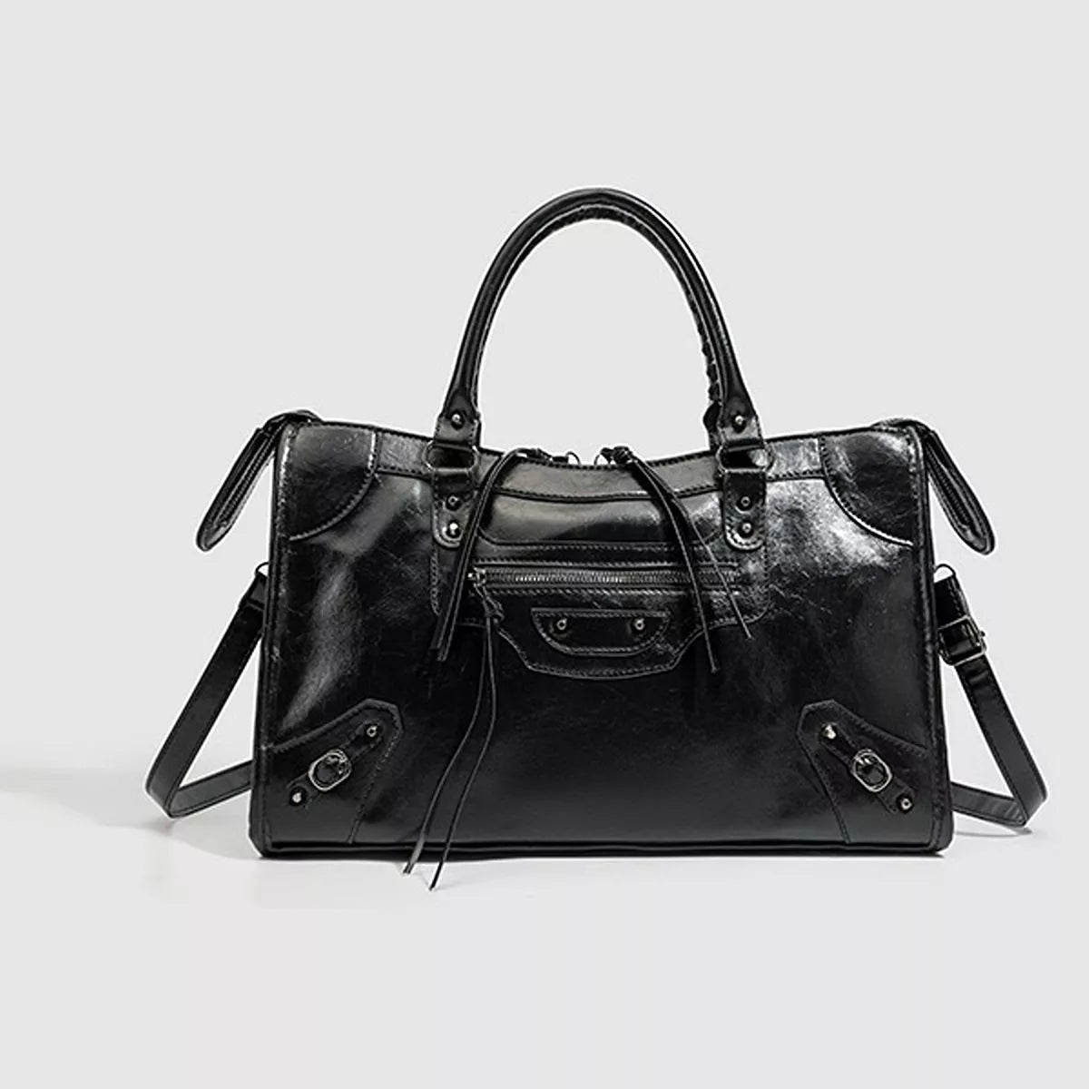 Black medium PU leather handbag with a structured rectangular silhouette, rounded top handles, front zip pockets, decorative straps, and a long shoulder strap.