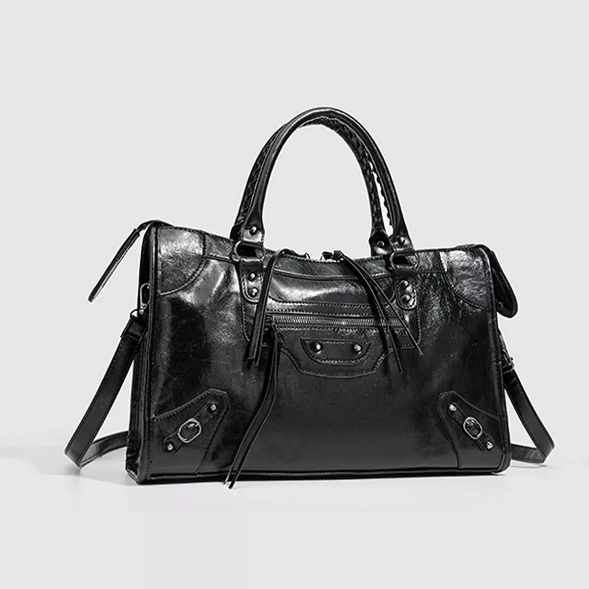 Black medium PU leather handbag with dual top handles, a structured silhouette, front zip pocket, decorative straps, and a long shoulder strap.