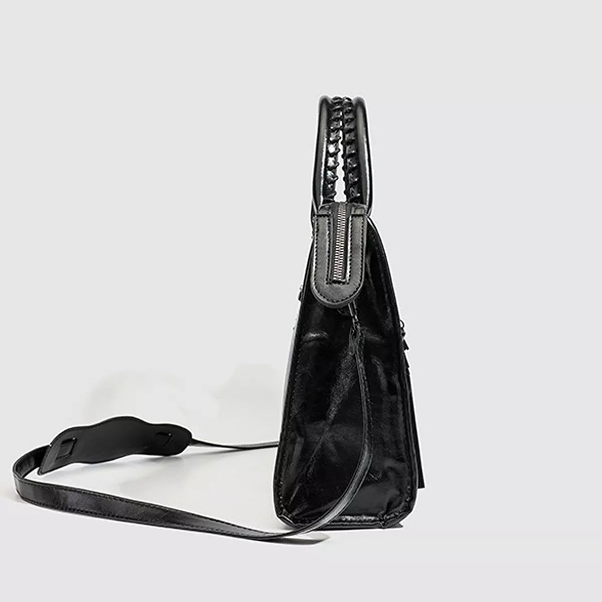 Black PU leather handbag shown in side profile with a structured silhouette, braided top handle, zip detail, stitched construction, and a long shoulder strap.