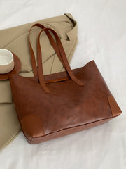 Brown PU leather medium tote bag with a softly structured silhouette, long shoulder straps, clean paneling, neat topstitching, and reinforced corner details.