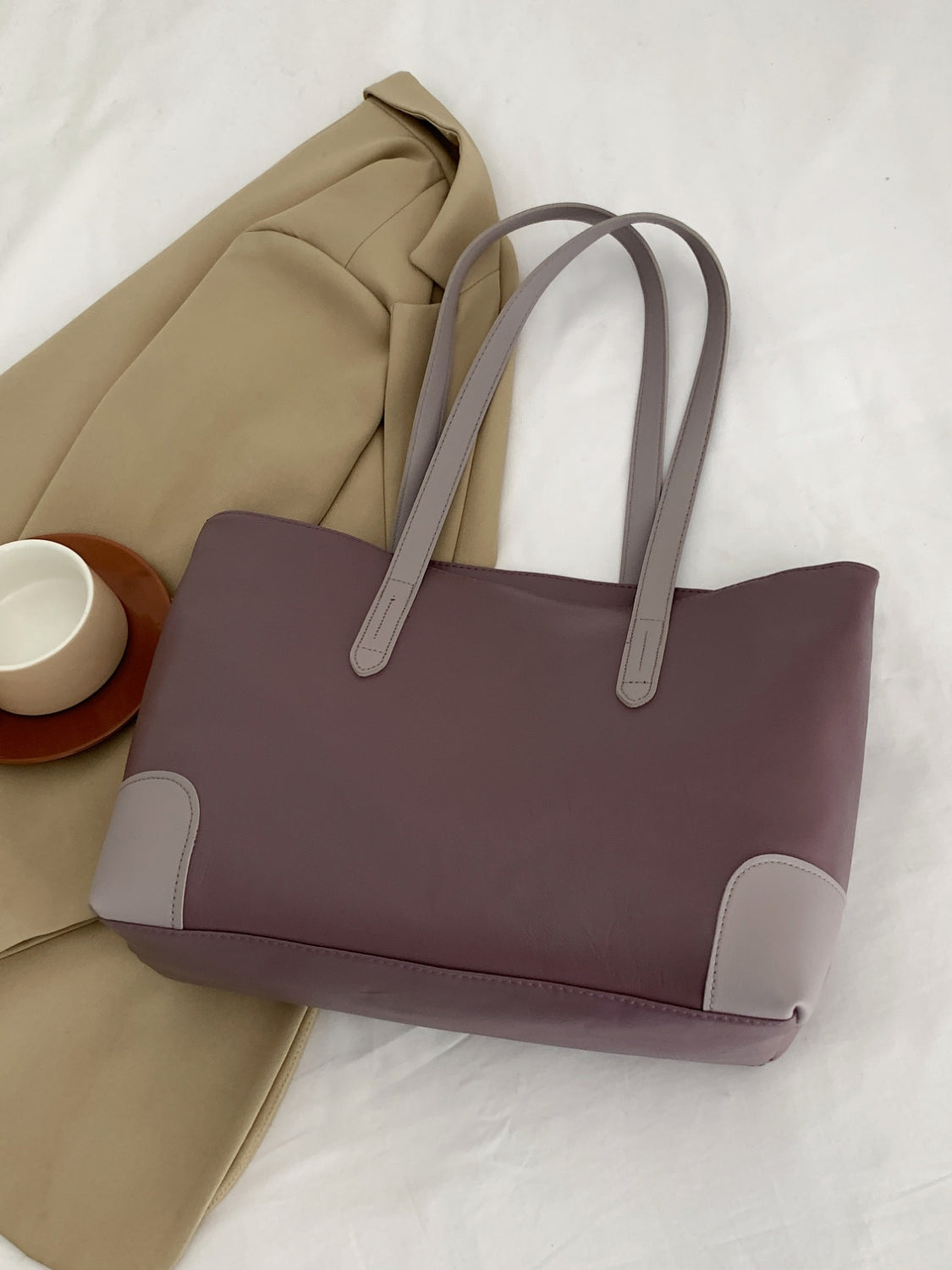 Mauve PU leather medium tote bag with a softly structured silhouette, long shoulder straps, clean topstitching, and contrasting reinforced corner details.