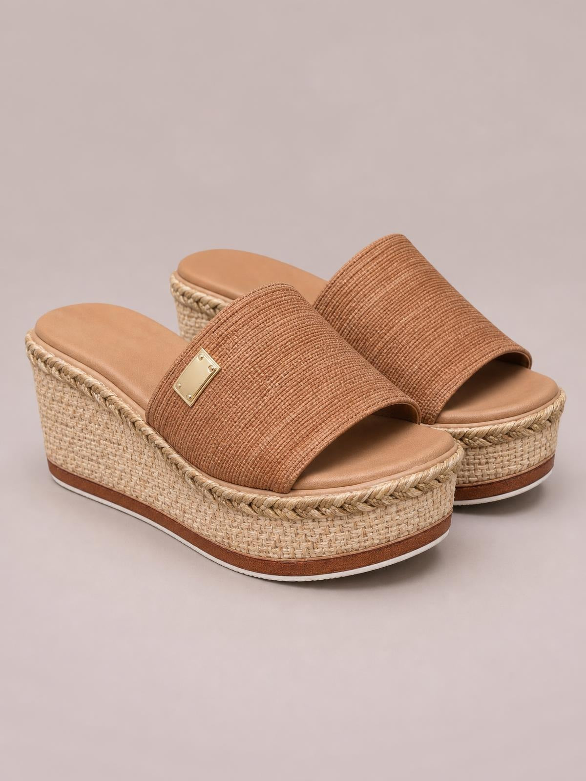 A pair of tan PU leather open-toe sandals with wide textured straps, woven espadrille wedge heels, platform soles, and braided trim.