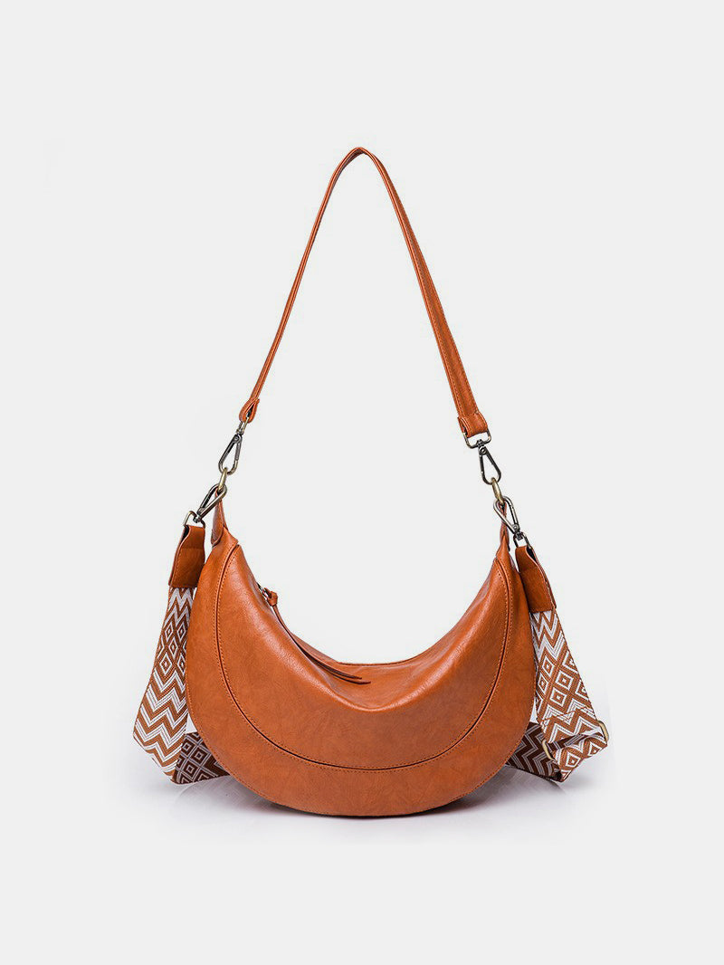 Large brown PU leather crossbody bag with a softly curved crescent silhouette, gathered sides, removable strap, and metal clip hardware.
