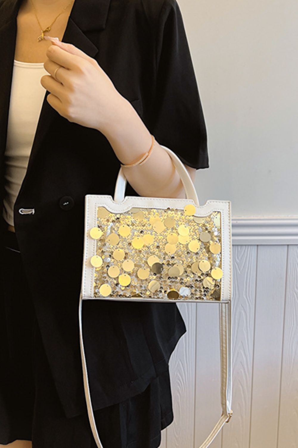 A model holds a small white PU leather handbag with a structured rectangular silhouette, rounded top handles, sparkling sequin front, and long shoulder strap.
