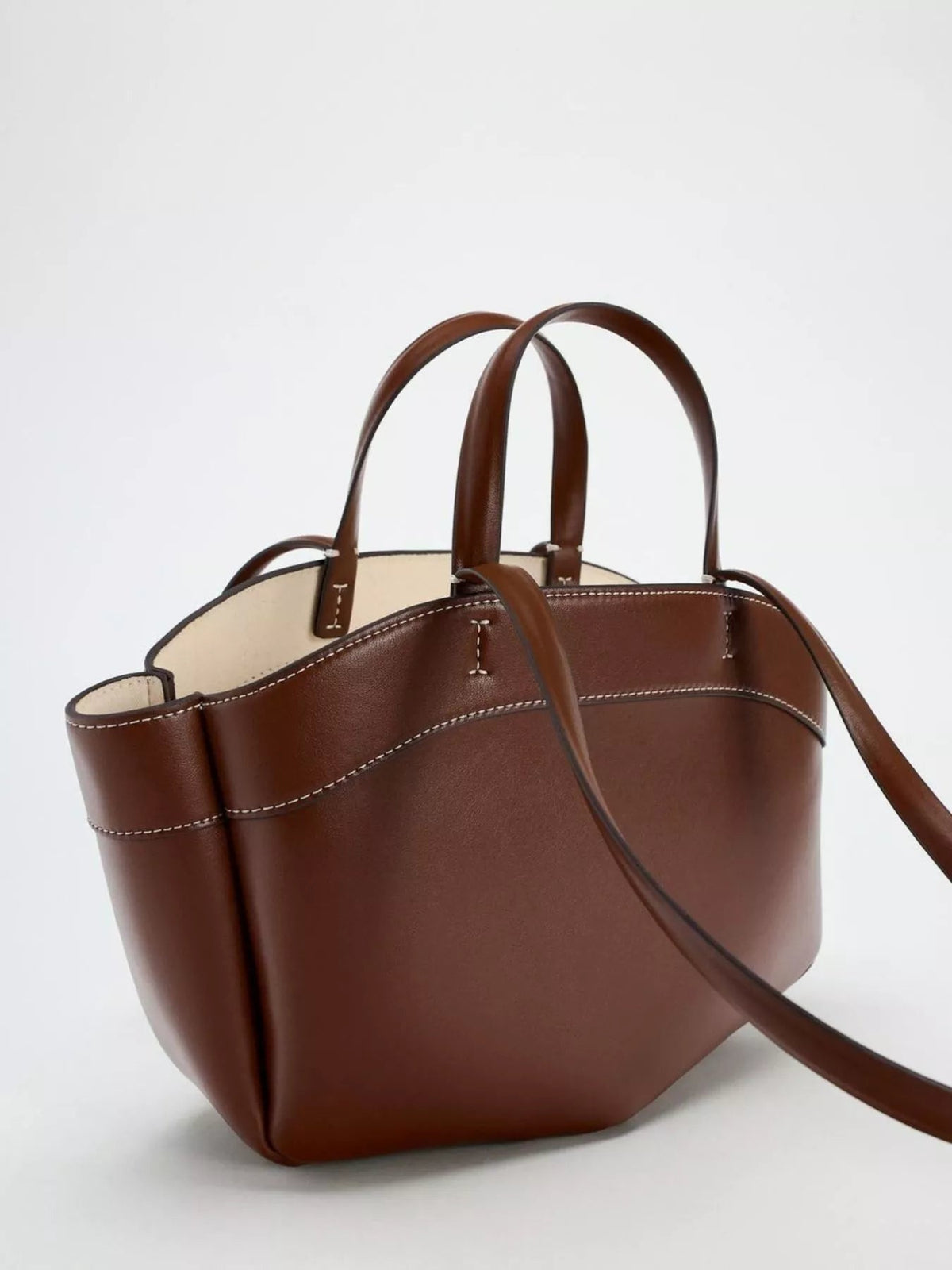 Large brown PU leather tote bag with an open top, double rounded handles, long shoulder strap, contrast stitching, and a softly structured silhouette.
