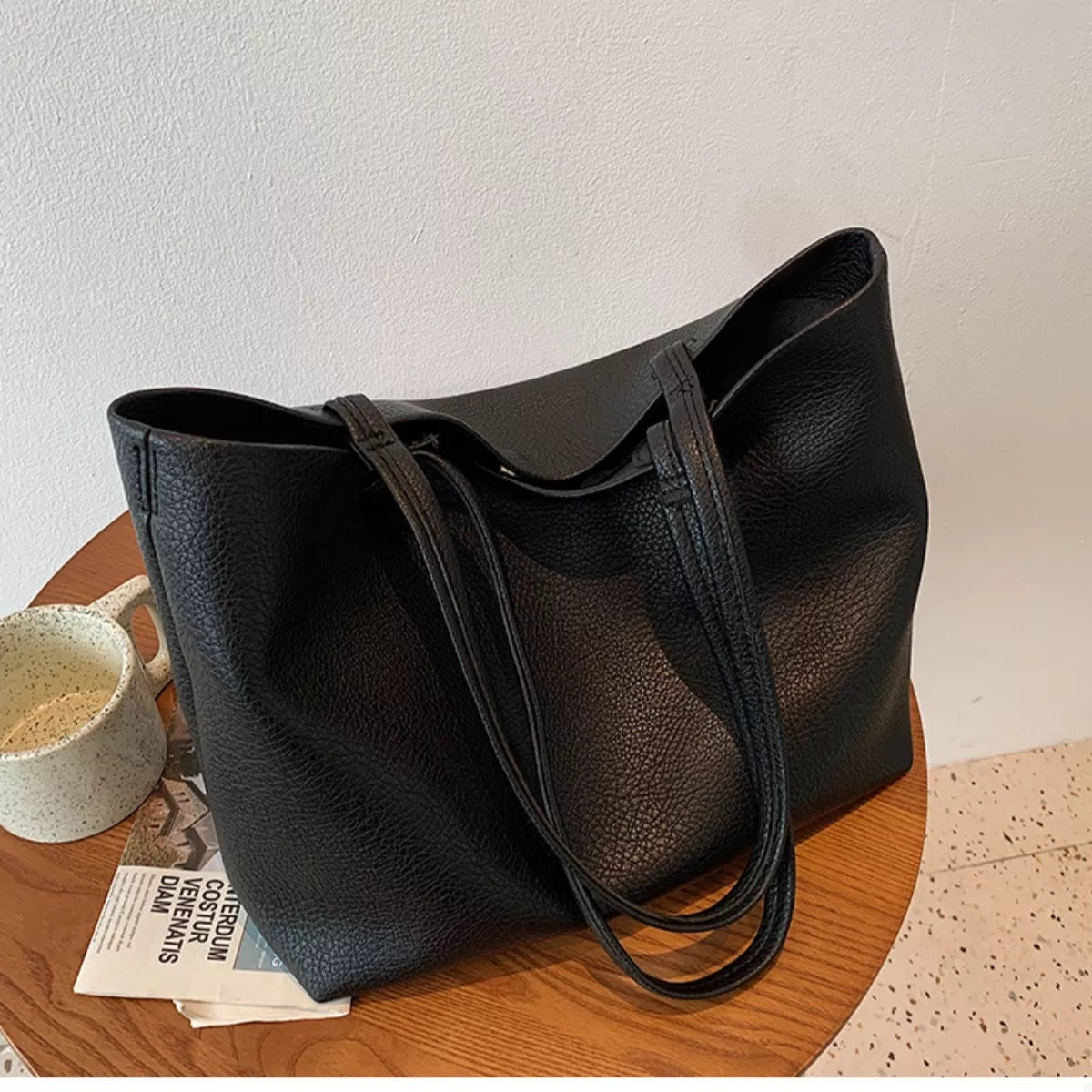 Large black PU leather tote bag with a softly structured silhouette, open top, pebbled finish, and two long shoulder straps.