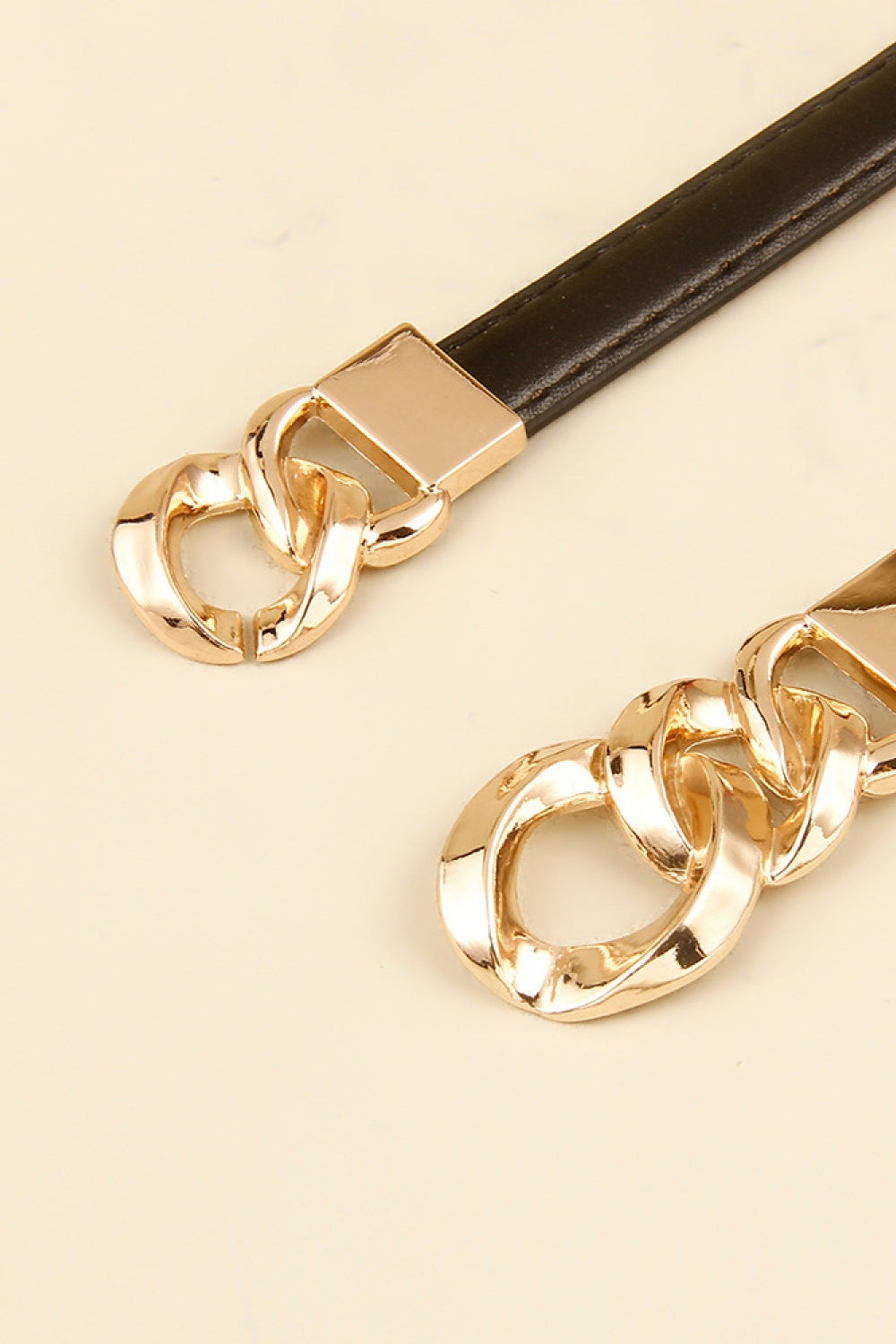 Black PU skinny belt with a streamlined strap and sculptural gold-tone zinc alloy chain-link buckle detail.