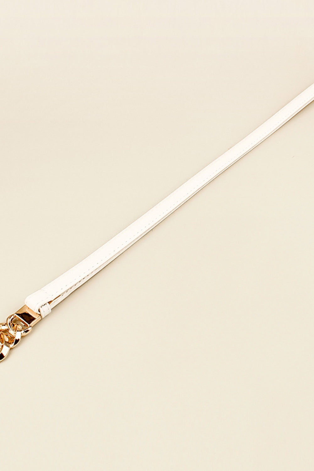 White PU skinny belt with a slender strap and gold-tone zinc alloy buckle featuring a sculptural chain-link detail.