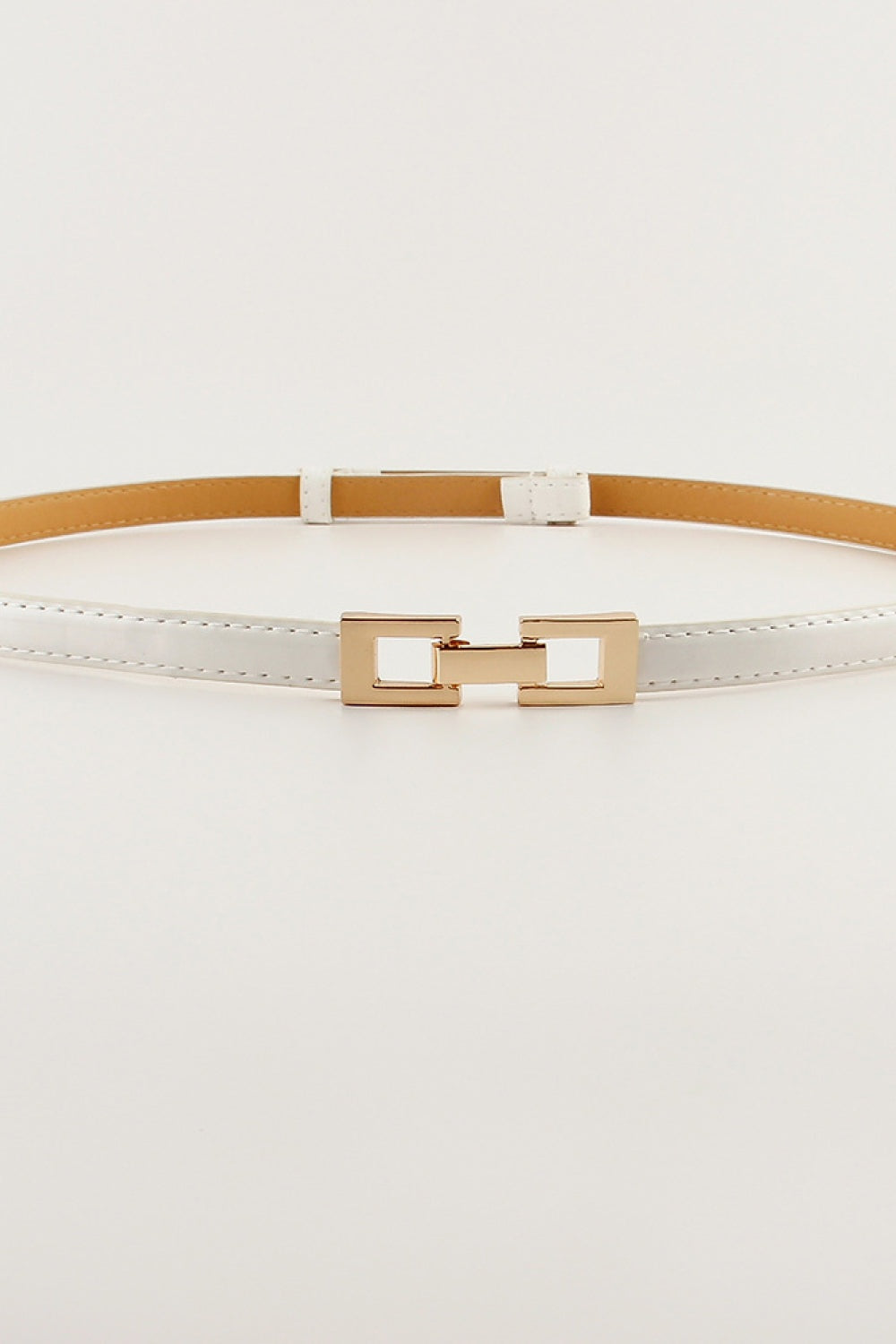 Slim white PU belt with stitched edges, a structured geometric gold-tone buckle, and a streamlined silhouette for defining the waist.