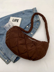 Large brown quilted crossbody bag with a softly structured crescent silhouette, plush volume, long strap, and zip-top closure.
