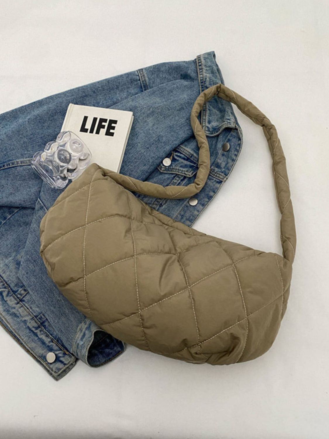 Large taupe quilted crossbody bag with a softly structured crescent silhouette, plush diamond stitching, and a long padded strap.