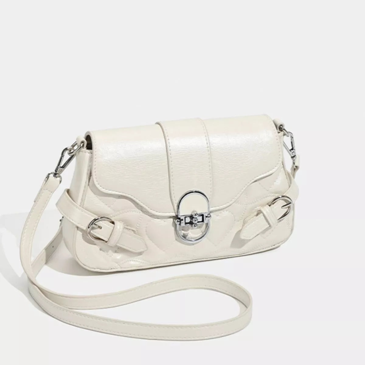 Small cream PU leather crossbody bag with a flap, quilted panels, silver buckle accents, central clasp, and an adjustable shoulder strap.