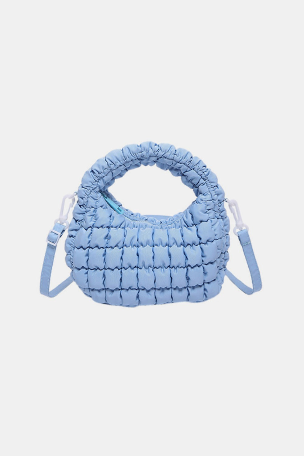 Light blue quilted puffy crossbody bag with a rounded silhouette, gathered padded top handle, compact construction, and removable shoulder strap.