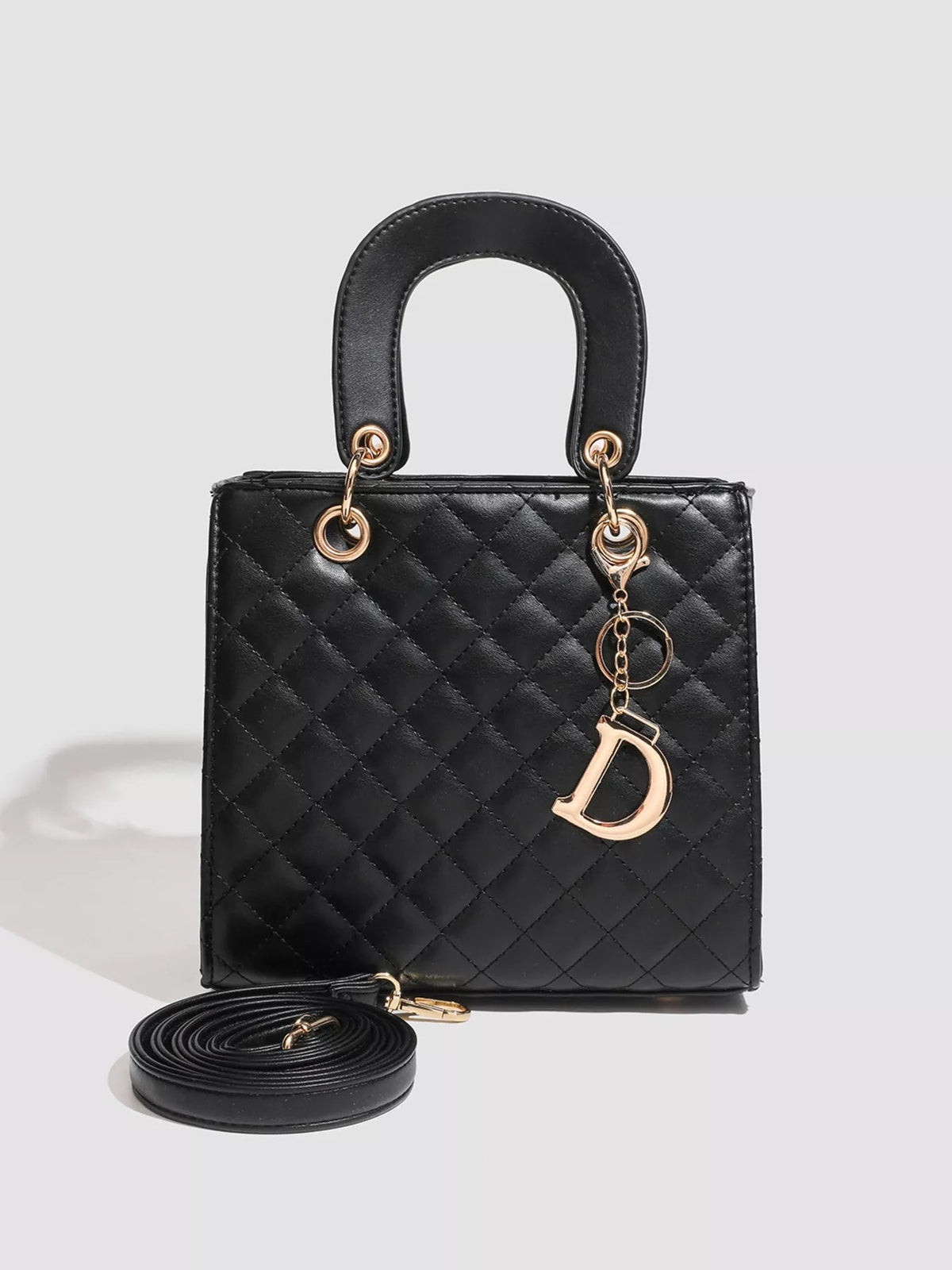 Black mini quilted PU leather top-handle handbag with diamond stitching, gold-tone hardware, a decorative charm, and a detachable shoulder strap.