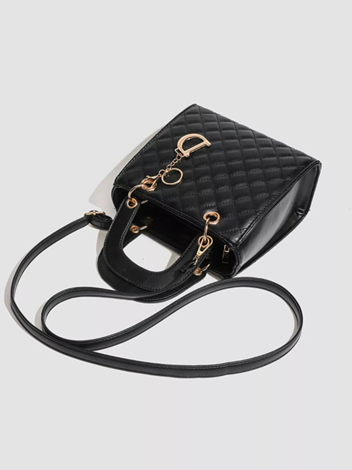 Black mini PU leather quilted top handle handbag with a structured silhouette, gold-tone hardware, and a long detachable shoulder strap.