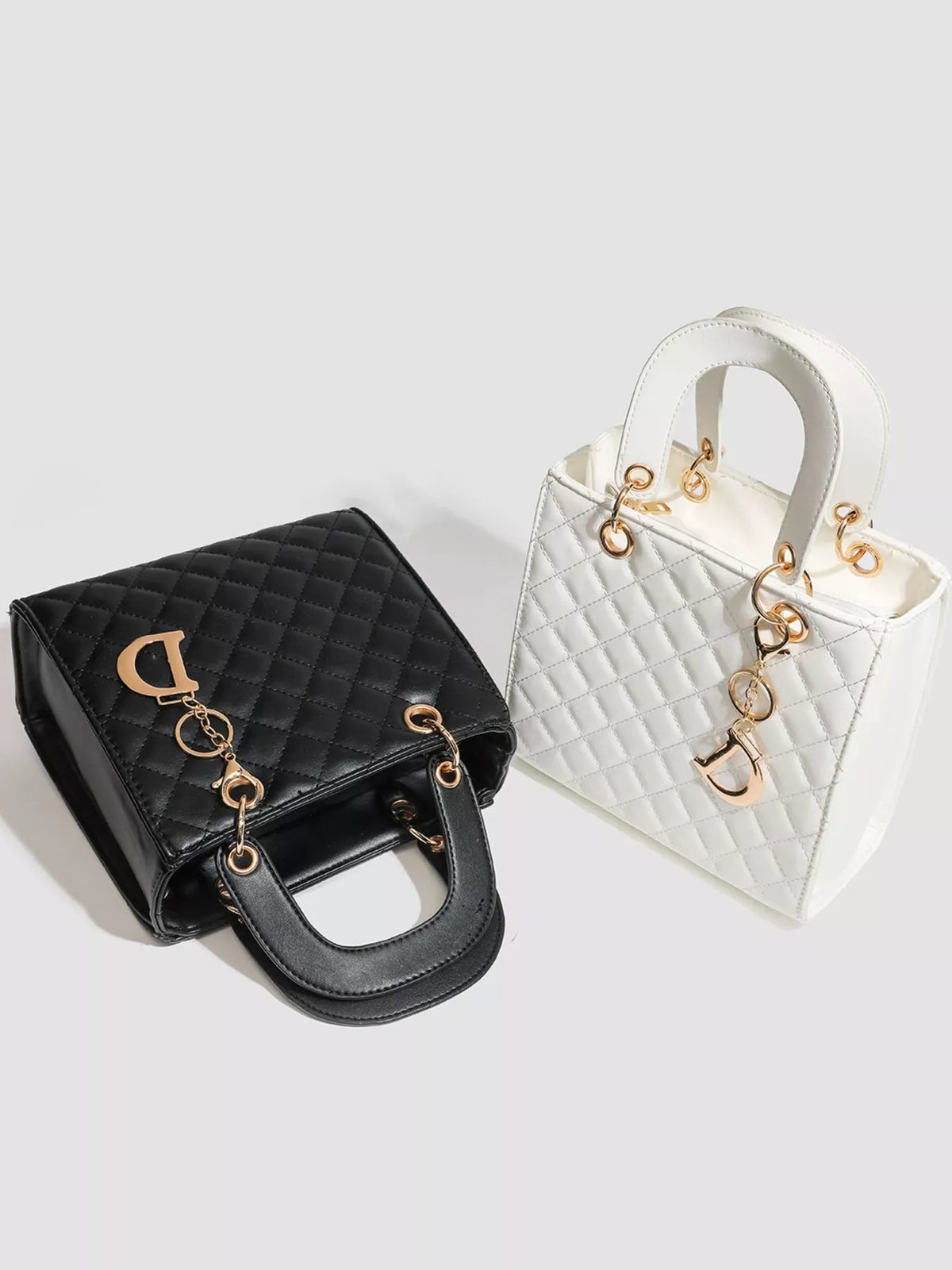 Two mini quilted top-handle handbags in black and white PU leather feature structured silhouettes, stitched diamond patterns, and gold-tone hardware.