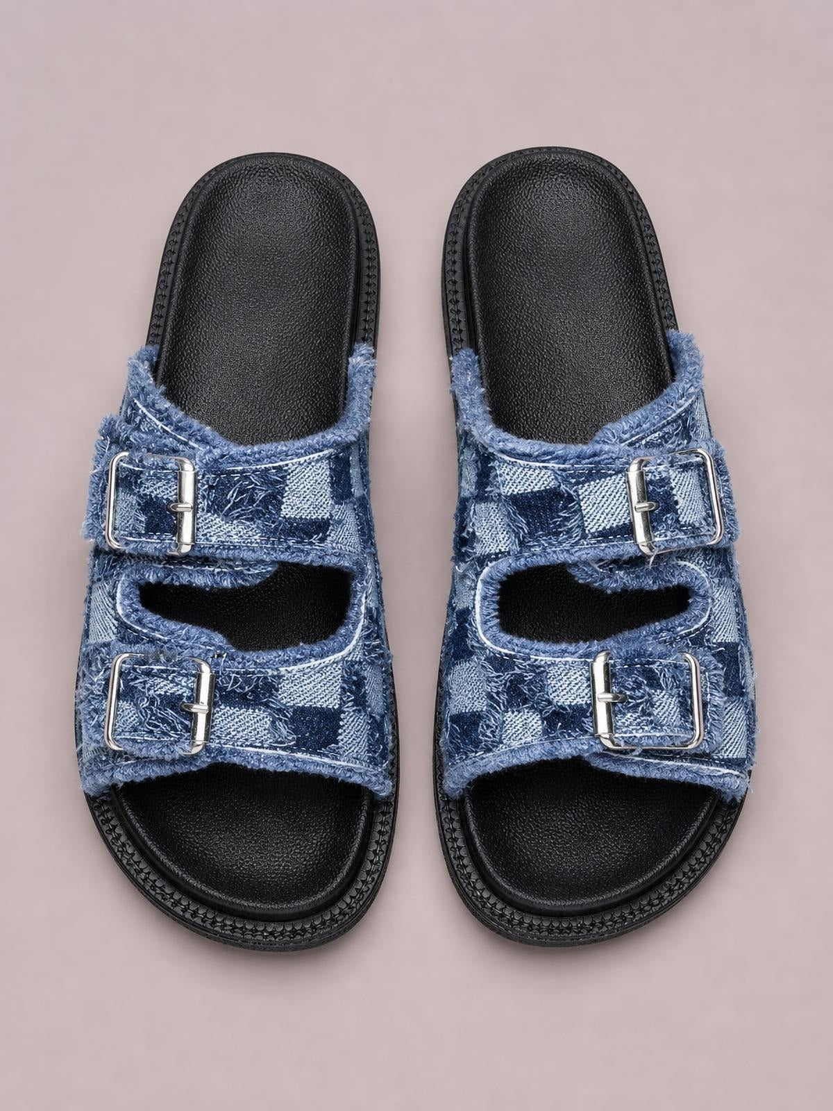 Blue checkered cloth buckle sandals feature raw edges, two silver buckles on each open-toe upper, cushioned black footbeds, and flat rubber soles.