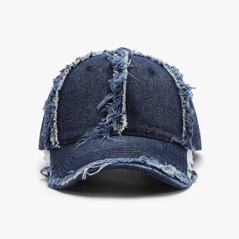Dark blue cotton baseball cap with a relaxed six-panel crown, curved brim, tonal stitching, and prominent raw, frayed hems along the seams and edge.