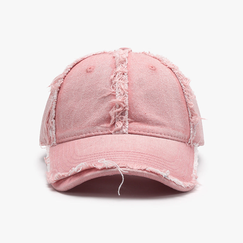 Pink cotton baseball cap with a relaxed six-panel crown, curved brim, raw frayed hems, tonal stitching, and visible ventilation eyelets.