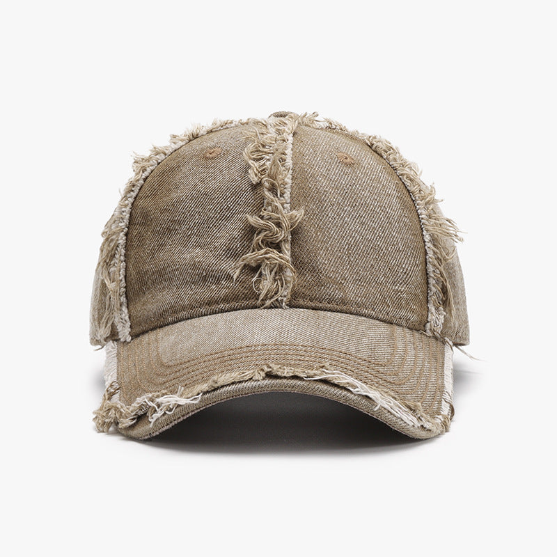 A taupe cotton baseball cap features a six-panel crown, curved brim, tonal stitching, and heavily frayed raw hems for a relaxed, lived-in finish.