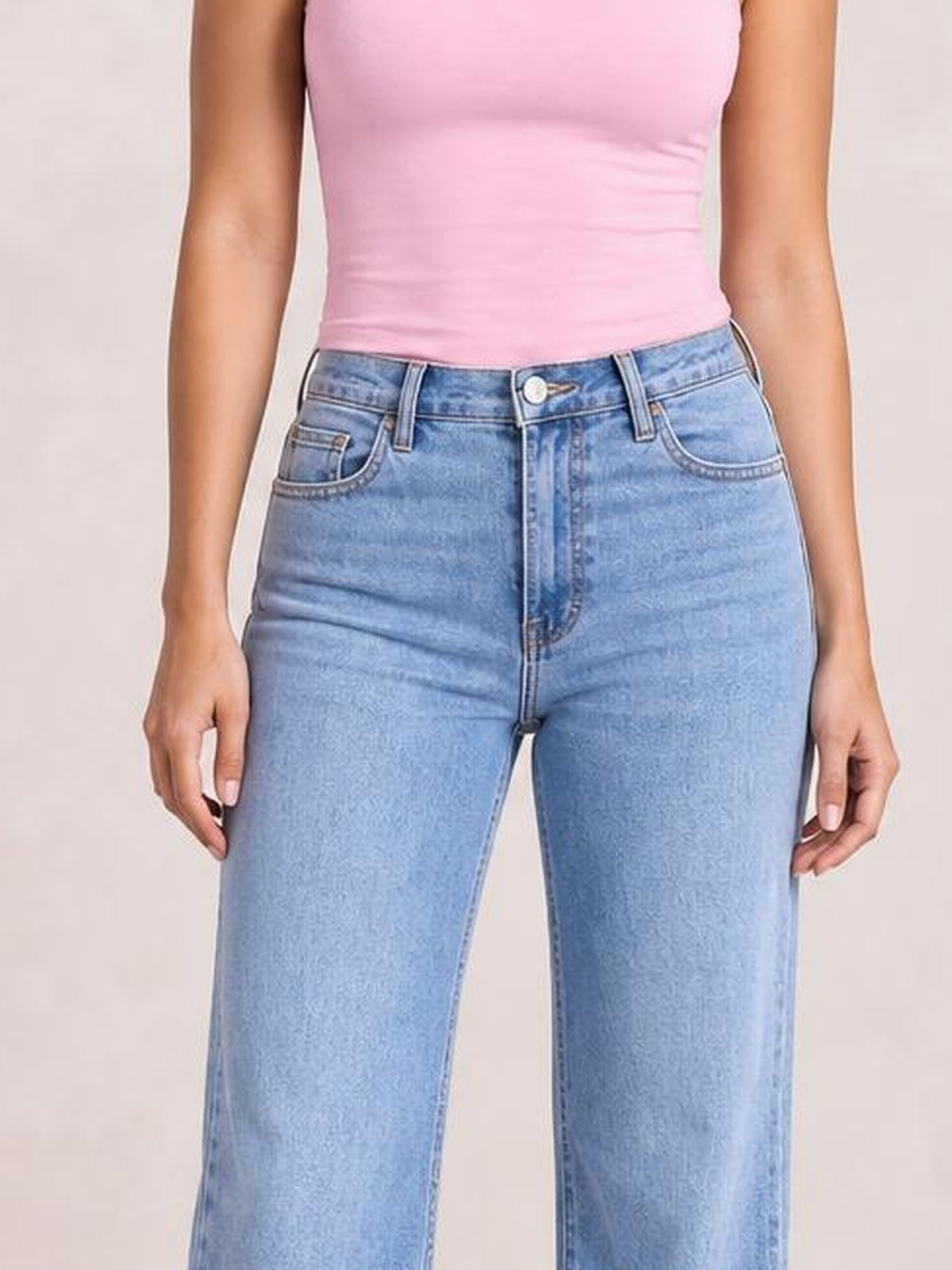 A model wears light blue loose-fit jeans with a high-rise waistband, button closure, belt loops, front pockets, and a straight-leg silhouette.