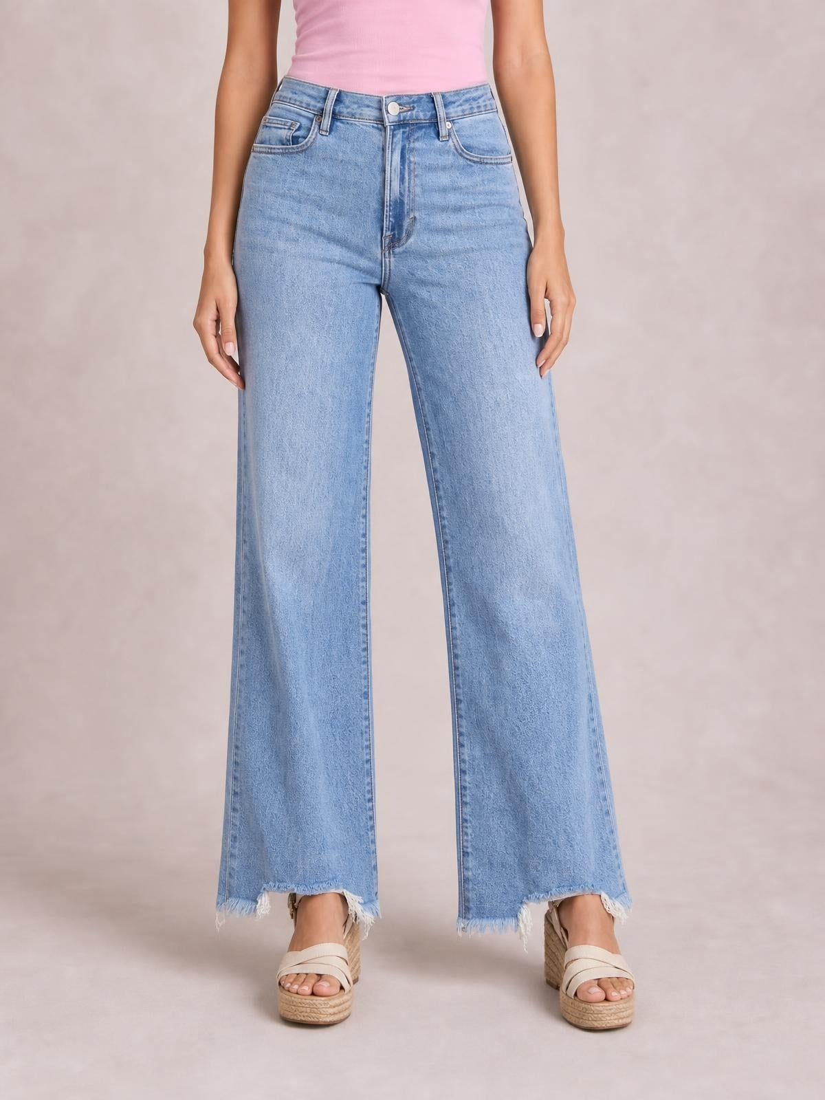 Model standing in light blue loose-fit jeans with a high waist, button closure, front pockets, straight wide legs, and frayed raw hems.