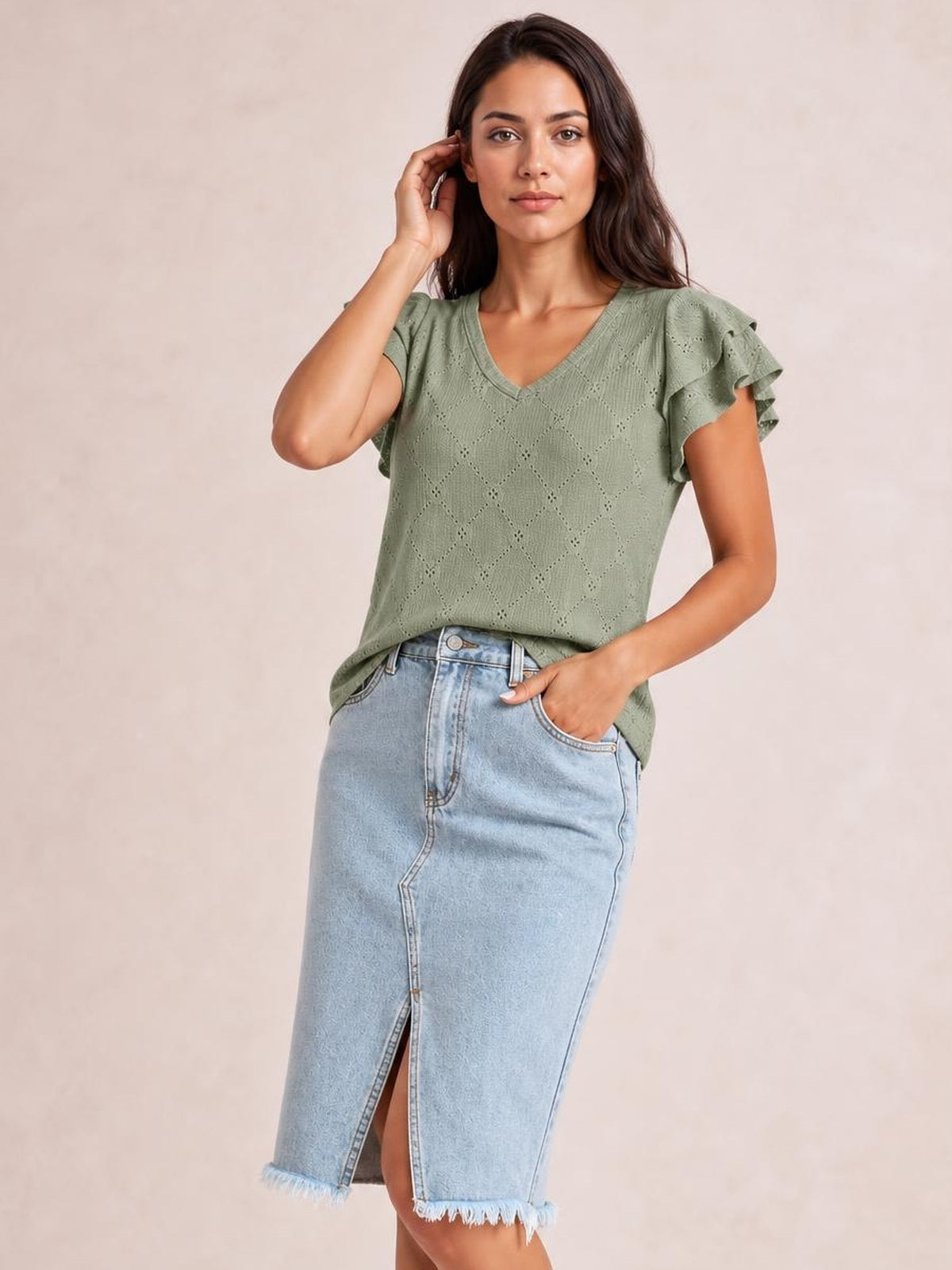 Model poses in a light-wash raw hem slit denim skirt with a buttoned front, pockets, and straight midi silhouette.