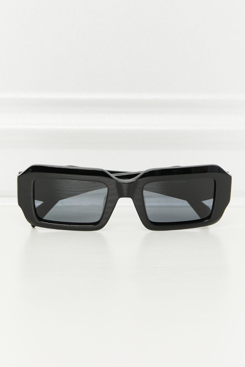 Sleek black rectangle sunglasses feature a bold full-rim acetate frame, softly squared silhouette, dark TAC polarized lenses, and matching temples.