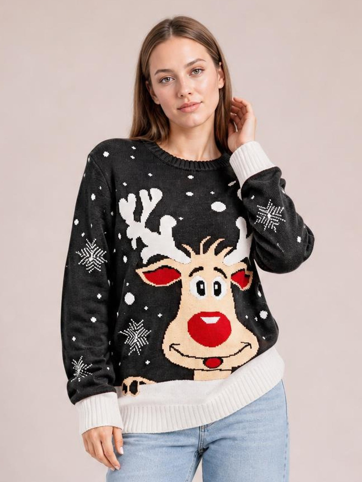 Model poses in a black reindeer round neck sweater with a festive front graphic, white ribbed cuffs and hem, and a relaxed silhouette.
