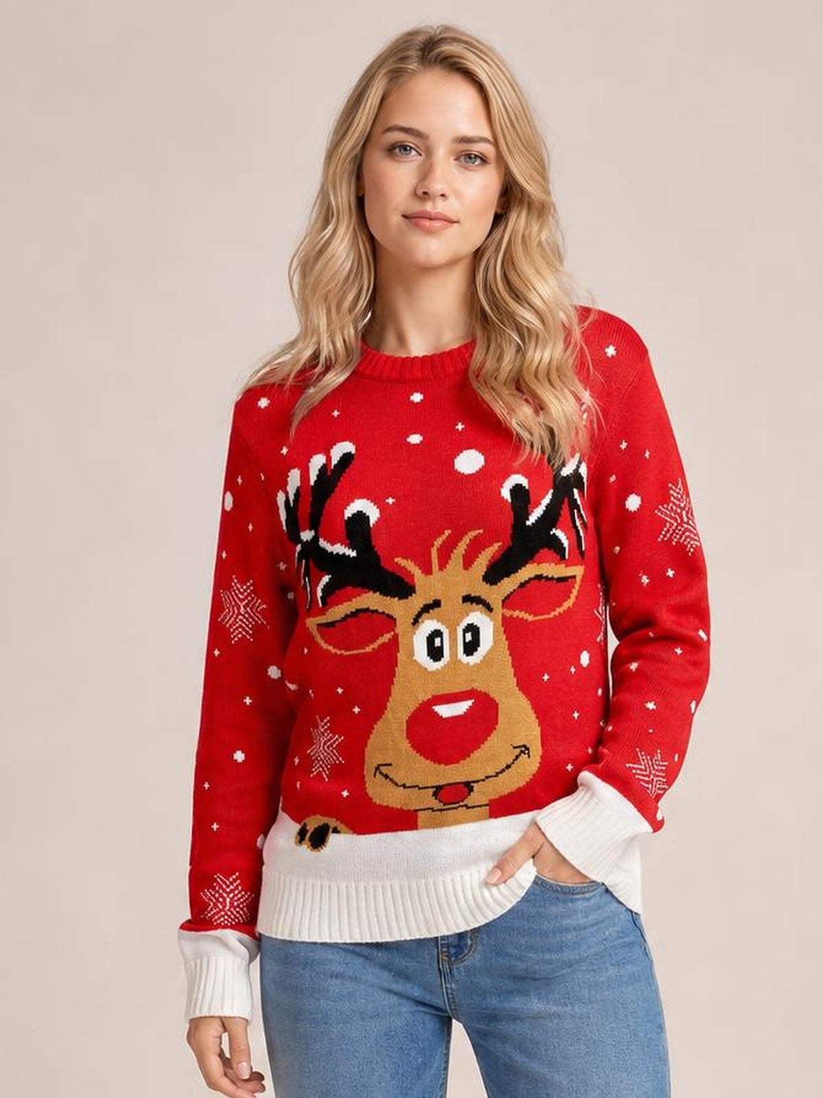 A woman poses in a red reindeer round neck sweater with long sleeves, white ribbed cuffs and hem, festive snowflake details, and a relaxed silhouette.