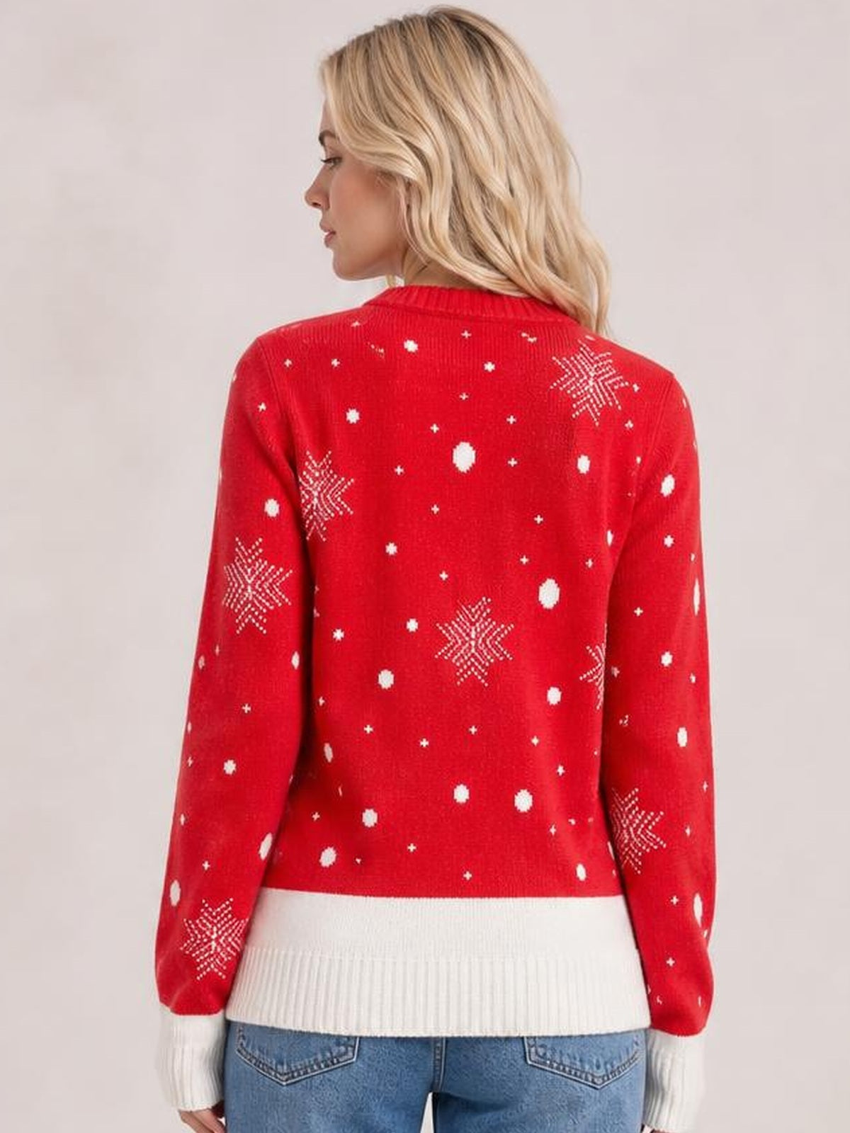 Model shown from the back wears a red Reindeer round neck sweater with white snowflake and dot motifs, long sleeves, ribbed cuffs, hem, and neckline.