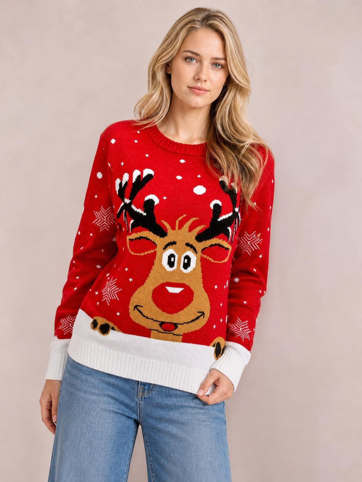 Model poses in a red Reindeer round neck sweater with a relaxed silhouette, white ribbed cuffs and hem, snowflake accents, and a festive knit reindeer design.