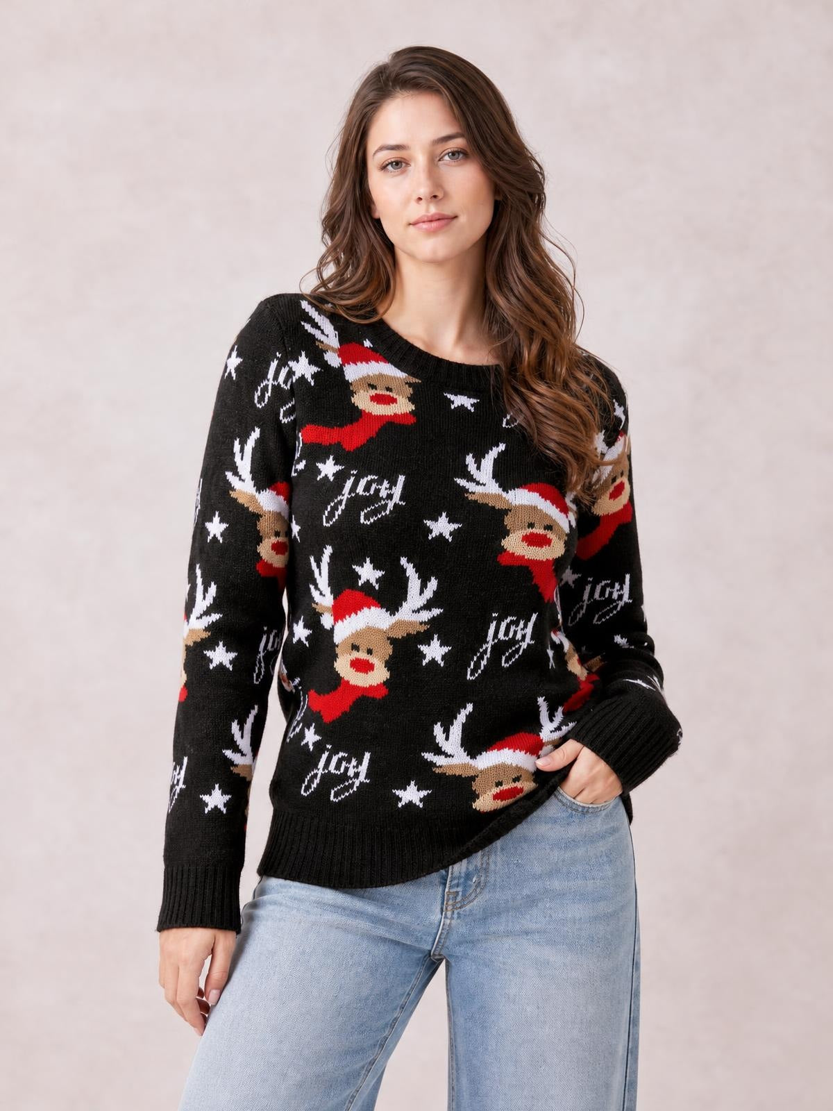 Model wearing a black reindeer round neck sweater with festive red, white, and tan motifs, long sleeves, ribbed cuffs and hem, and a relaxed silhouette.