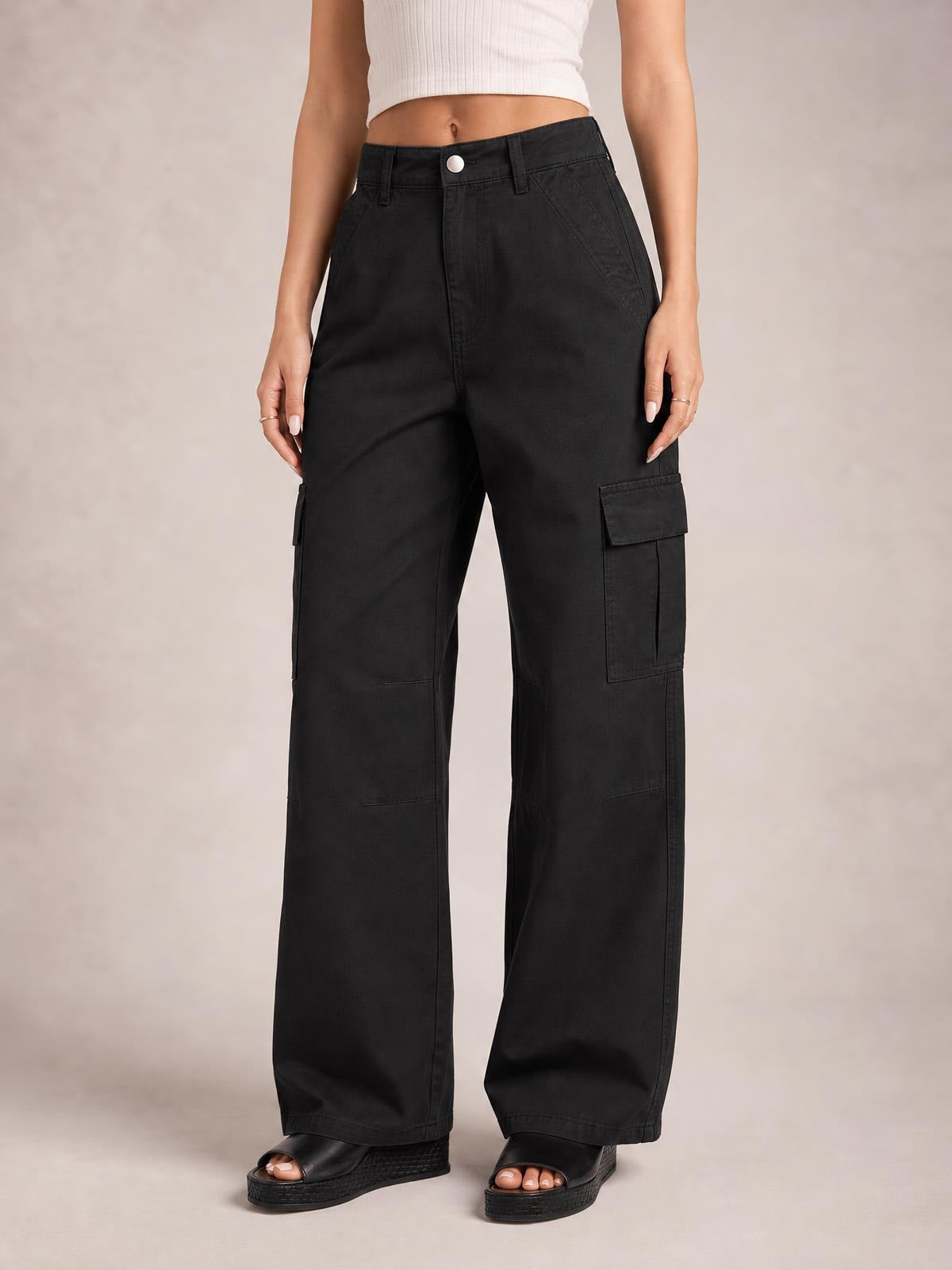 Model stands facing forward in black relaxed-fit cargo jeans with a button waistband, belt loops, slanted pockets, and flap utility pockets on wide legs.
