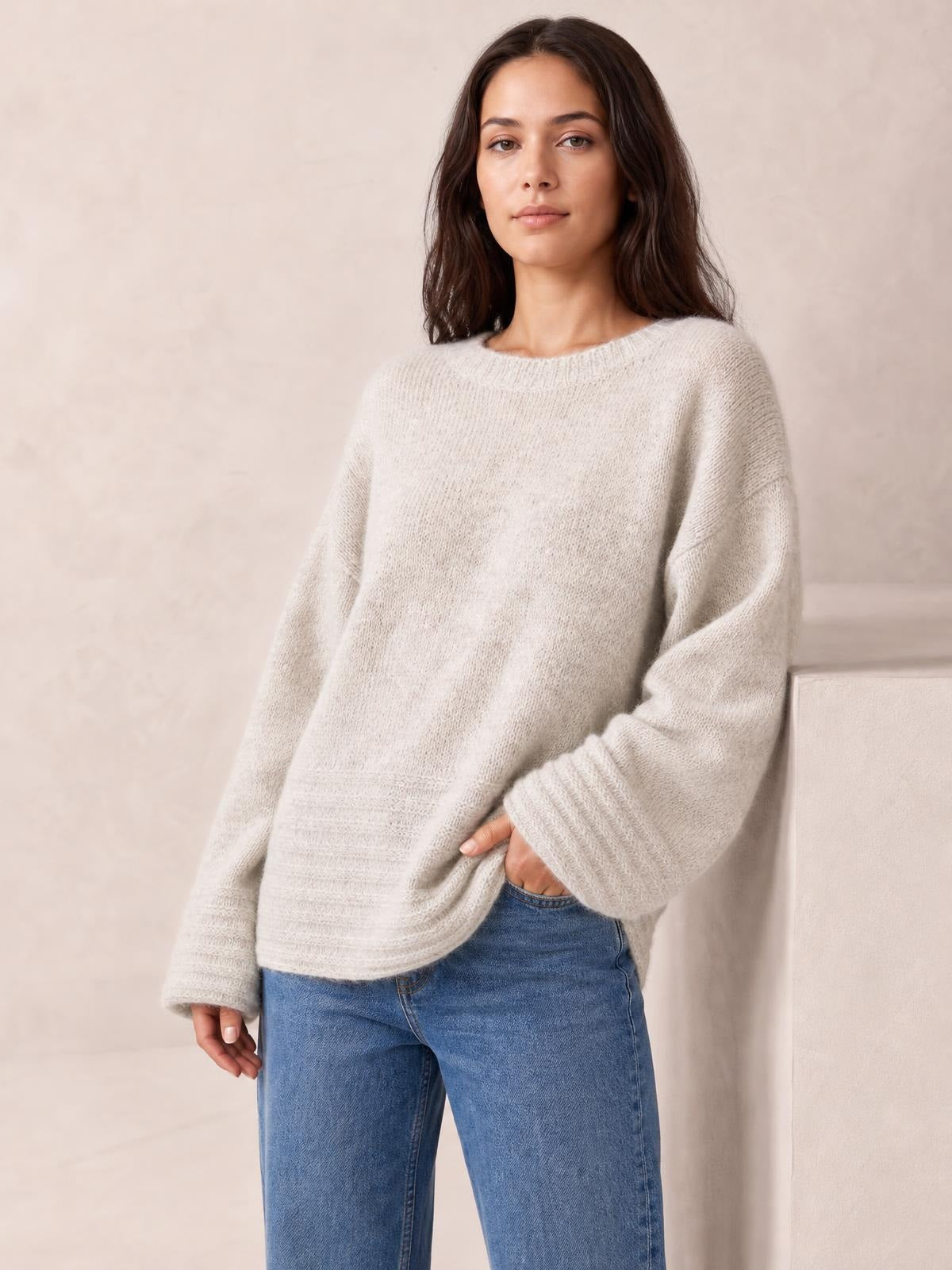 Model wears a relaxed-fit light beige round-neck sweater with a soft knit texture, dropped shoulders, wide sleeves, and a straight silhouette.