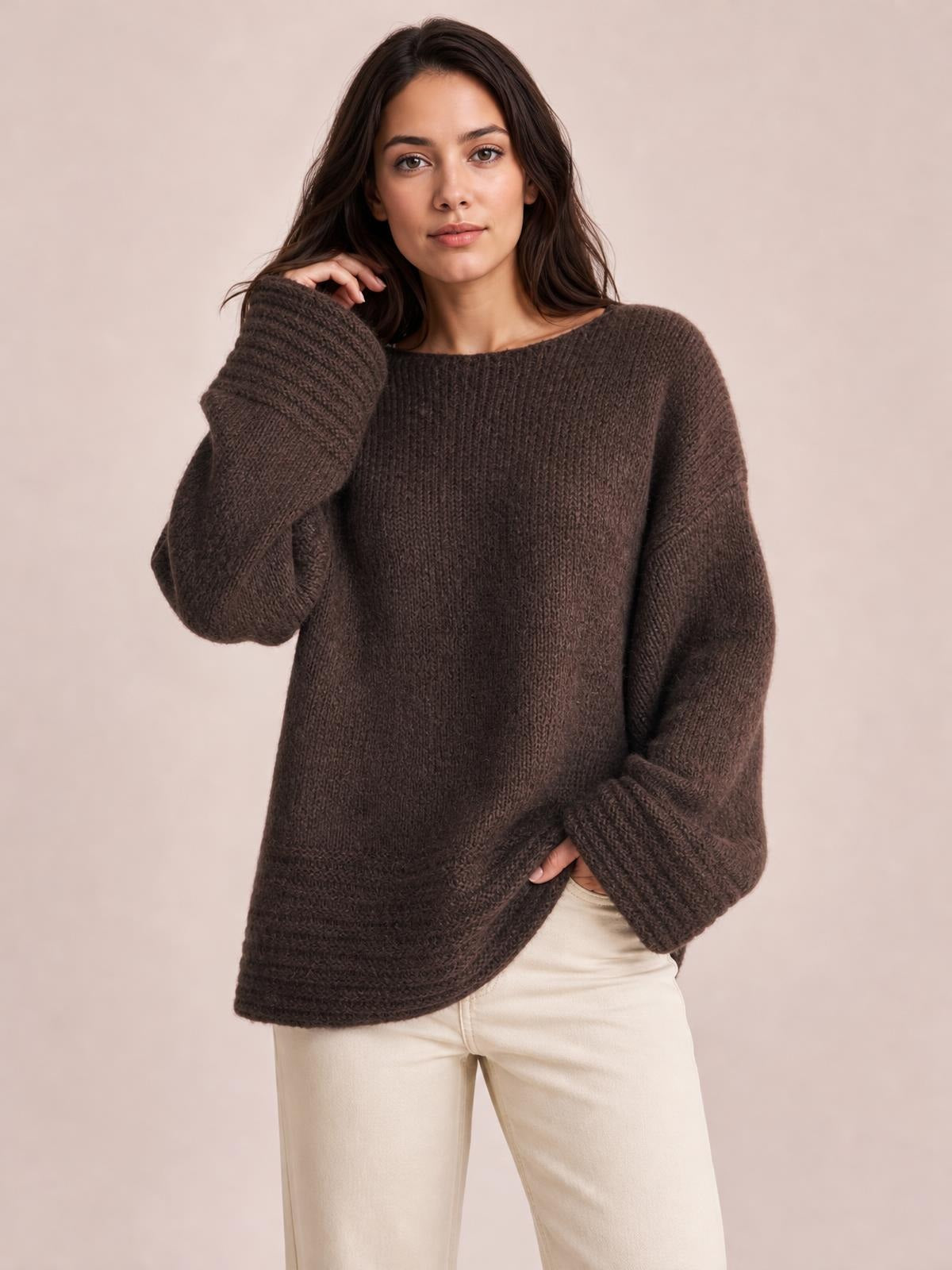 Model poses in a relaxed fit dark brown round neck sweater with a loose silhouette, long sleeves, and subtle ribbed knit texture.