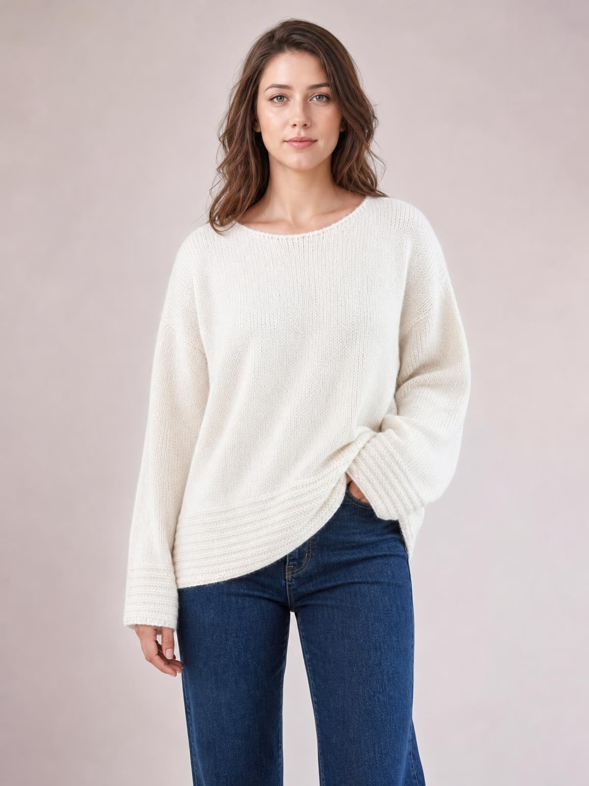 Model wears a relaxed-fit ivory round-neck sweater with long sleeves, ribbed cuffs and hem, a loose silhouette, and one hand resting at the hip.