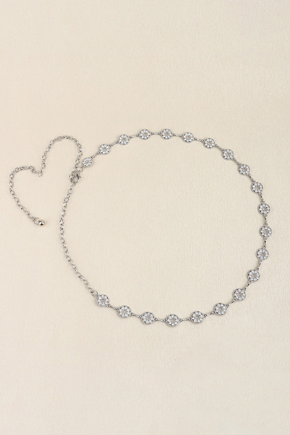 Slim silver-tone zinc alloy belt featuring a linked chain design, circular rhinestone accents, and a trailing chain extension for elegant draped styling.