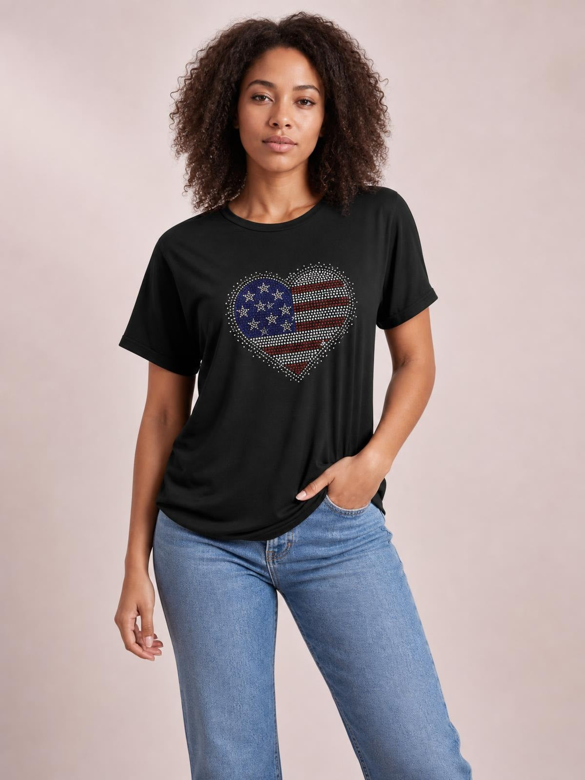 A model stands in a black rhinestone heart round-neck short-sleeve T-shirt with a relaxed silhouette, one hand resting at her jeans pocket.